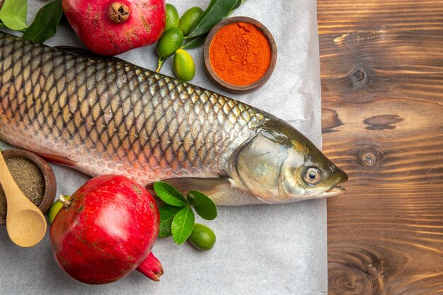 Top view fresh fish with pomegranates on wooden table food seafood dish ocean