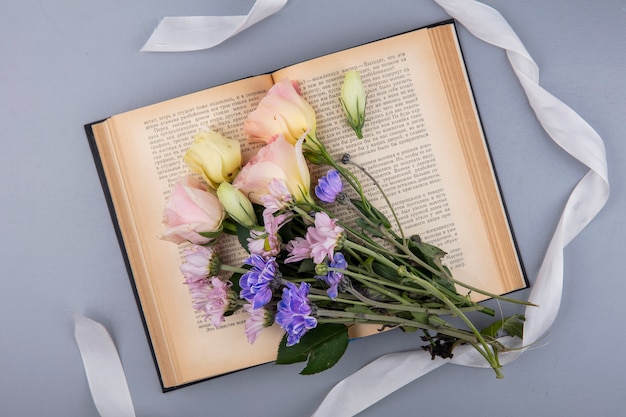 Top view of fresh flowers with white ribbon isolated on a gray background