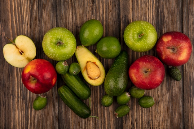 Vista dall'alto di cibi freschi come mele verdi e rosse feijoas avocado cetrioli isolati su una superficie di legno