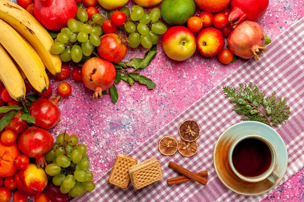 Вид сверху композиция из свежих фруктов, красочные фрукты с чашкой чая и вафлями на розовой поверхности
