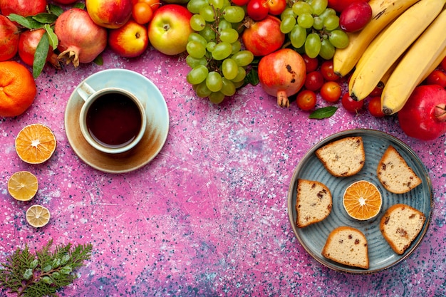 Foto gratuita vista dall'alto composizione di frutta fresca frutta colorata con deliziose torte affettate sulla scrivania rosa