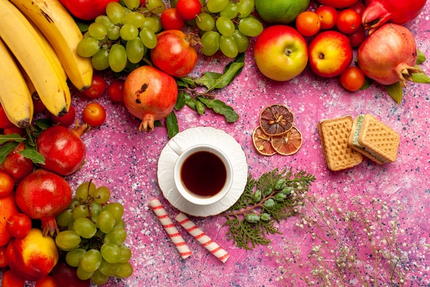 Вид сверху композиция из свежих фруктов, красочные фрукты с вафлями и чашка чая на розовой поверхности