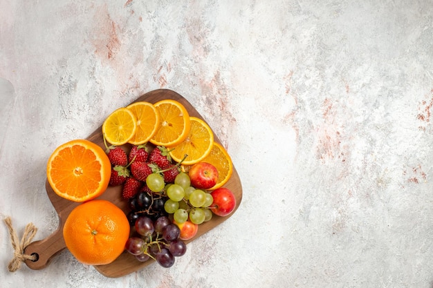 Vista dall'alto della composizione di frutta fresca arance uva e fragole sulla superficie bianca