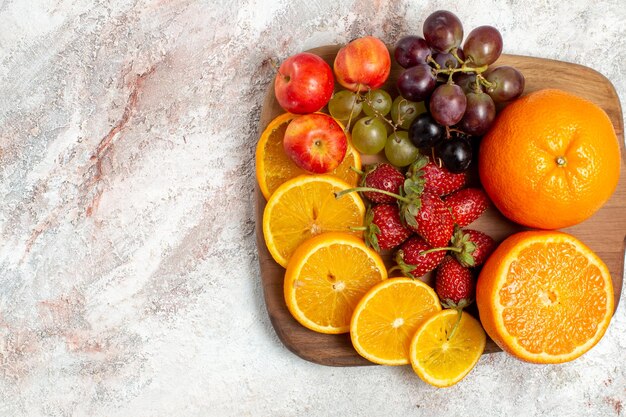 Top view of fresh fruit composition oranges grapes and strawberries on white surface