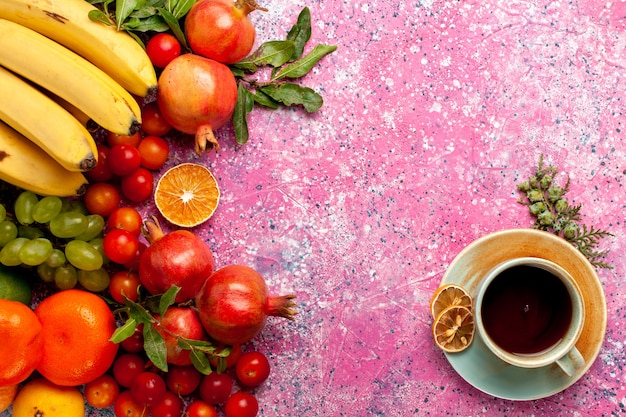 Vista dall'alto composizione di frutta fresca con una tazza di tè sulla scrivania rosa chiaro