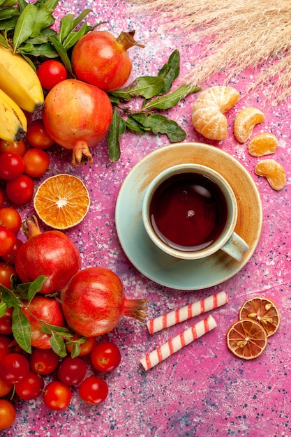 Top view fresh fruit composition with cup of tea on light pink surface