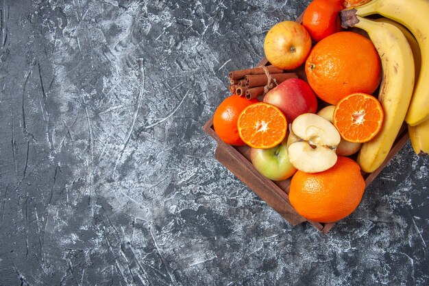 Top view fresh fruits and cinnamon sticks on wooden tray on table with free space