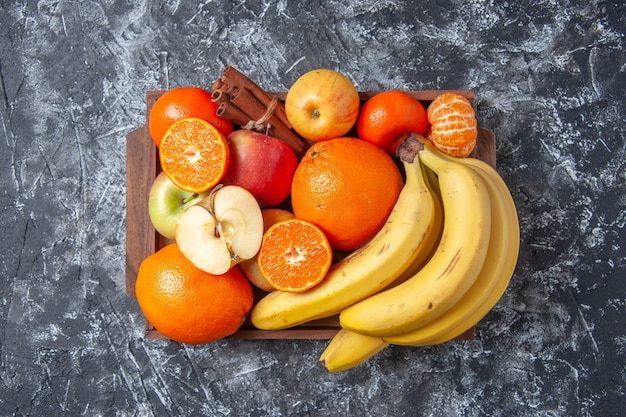 Top view fresh fruits and cinnamon sticks on wooden tray on table