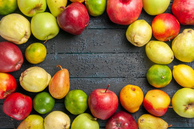 Top view fresh fruits composition apples pears and tangerines on dark-blue desk fruits ripe tree color mellow many fresh