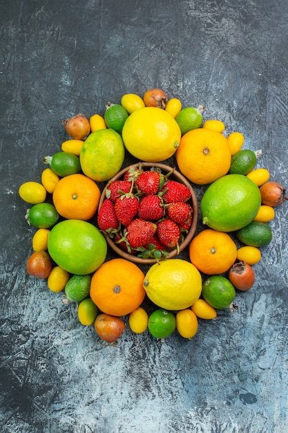 Top view fresh fruits composition with red strawberries on grey background