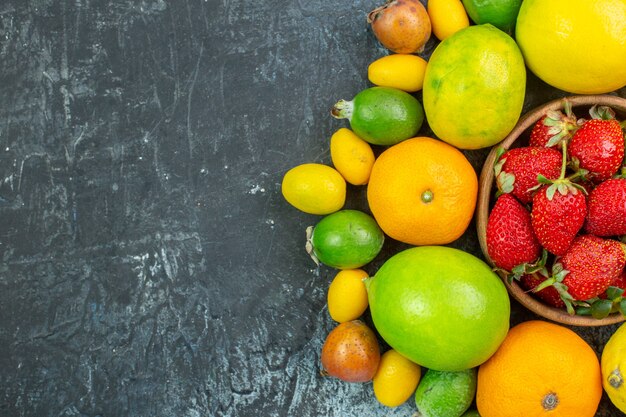 Top view fresh fruits composition with red strawberries on the grey background