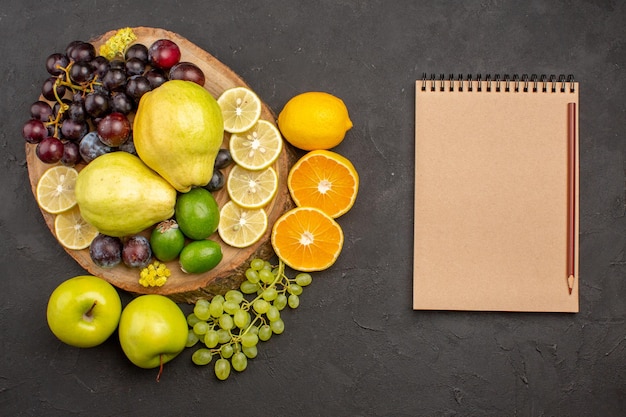 Top view fresh fruits grapes lemon slices plums and quinces on a dark surface ripe fresh fruits health vitamine tree