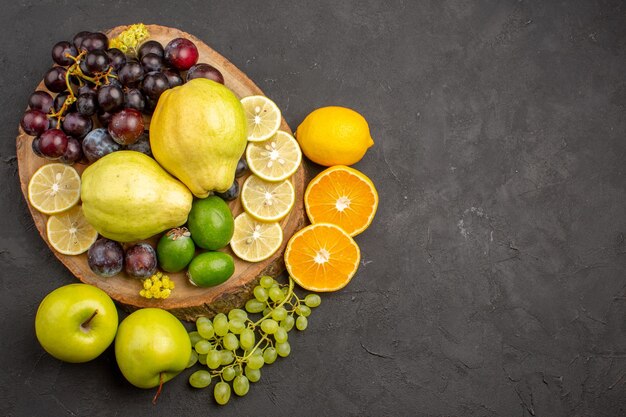 상위 뷰 신선한 과일 포도 레몬 슬라이스 자두와 quinces 어두운 표면 익은 신선한 과일 건강 비타민 나무