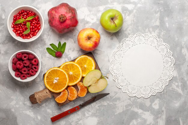 Top view fresh fruits oranges raspberries and pomegranates on white desk fruits fresh mellow vitamine juice tropical exotic