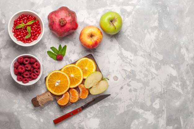 Top view fresh fruits oranges raspberries and pomegranates on white surface fruit fresh mellow vitamine juice tropical exotic