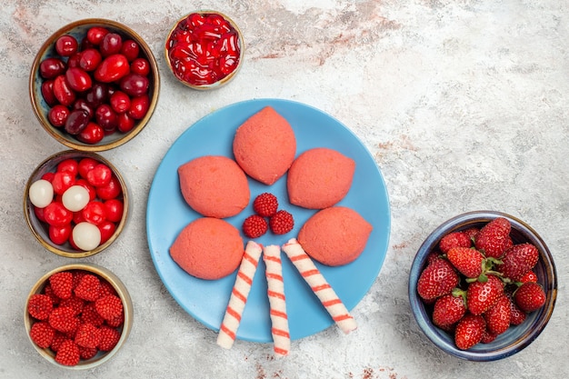 Top view fresh fruits raspberries strawberries and dogwoods with cookies on white desk