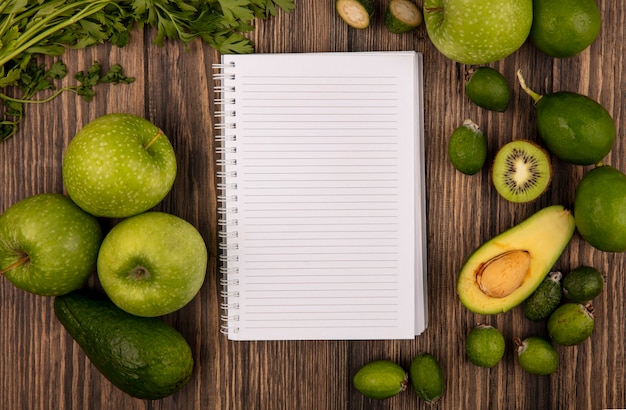 Vista dall'alto di frutta fresca come mele verdi lime feijoas avocado e prezzemolo isolato su una superficie in legno con spazio di copia