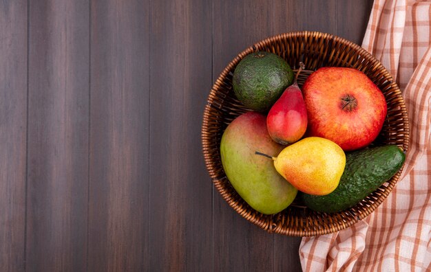 Top view of fresh fruits such as pomegranate pear mango on bucket on wood with copy space