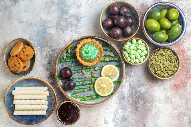 Top view fresh fruits with biscuits and little cake