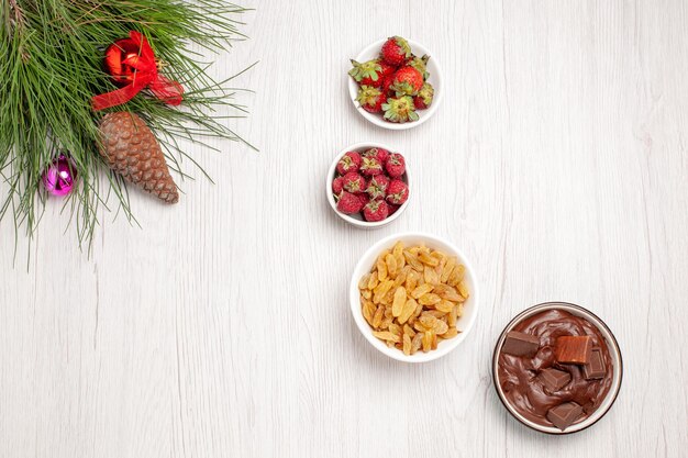 Вид сверху свежих фруктов с изюмом и шоколадным десертом на белом столе