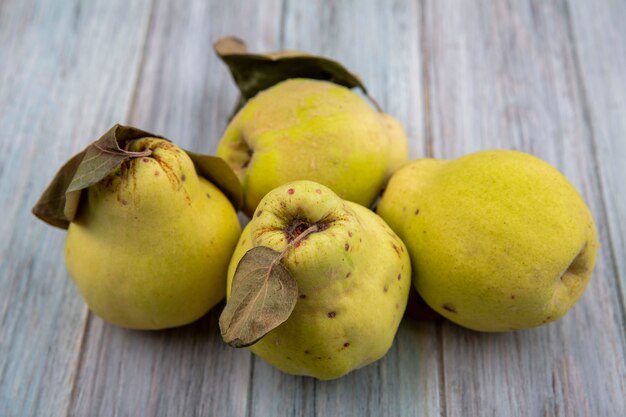 Top view of fresh golden quinces with leaves on a grey background