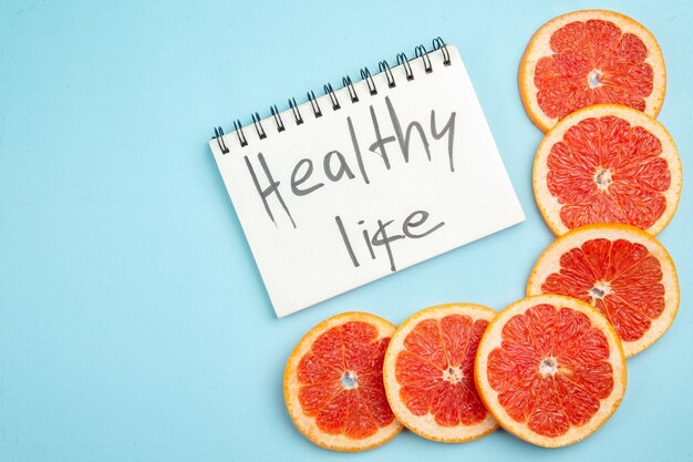 Top view fresh grapefruits fruit slices with healthy life writing on blue background