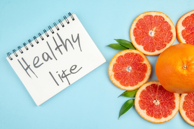 Top view fresh grapefruits fruit slices with healthy life writing on blue background