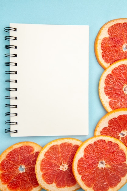 Top view fresh grapefruits fruit slices with notepad on blue background