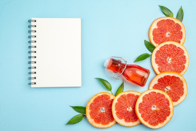 Top view fresh grapefruits fruit slices with notepad on blue background