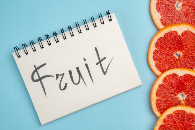 Free photo top view fresh grapefruits lined with fruit writing on blue background