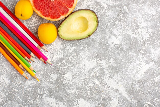 Top view fresh grapefruits mellow and juicy citruses with pencils on white surface