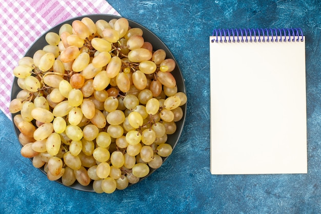 Free photo top view fresh grapes inside plate on a blue table