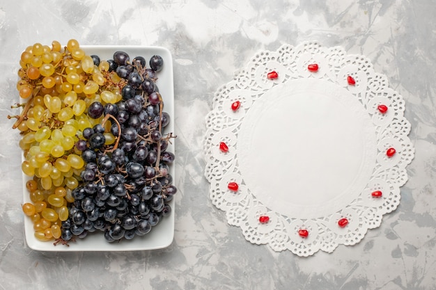 Foto gratuita vista dall'alto uva fresca frutta dolce e succosa all'interno del piatto sulla superficie bianca frutta albero di succo d'uva vino fresco