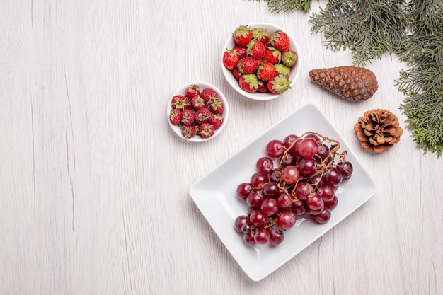 Free photo top view of fresh grapes with berries on wooden table