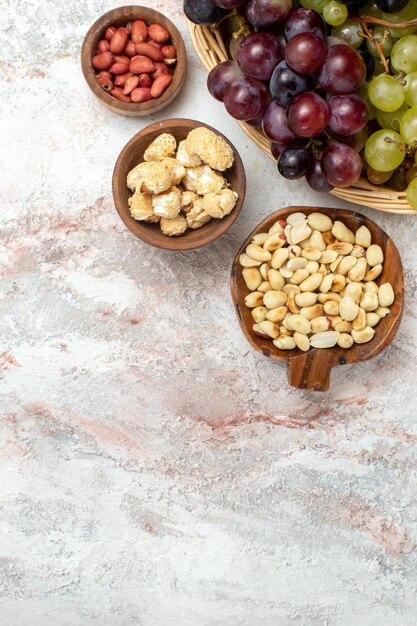 Top view of fresh grapes with nuts on white surface