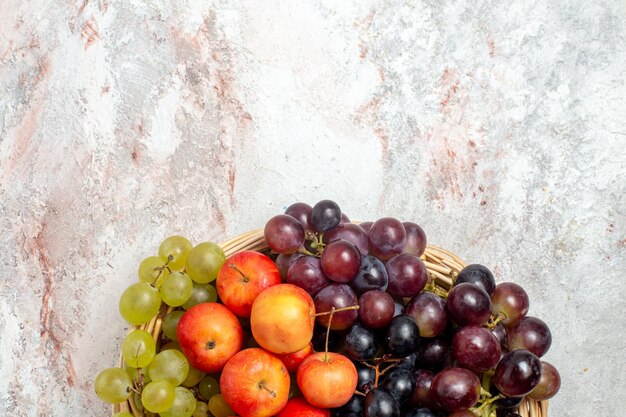 Top view of fresh grapes with plums on light white surface