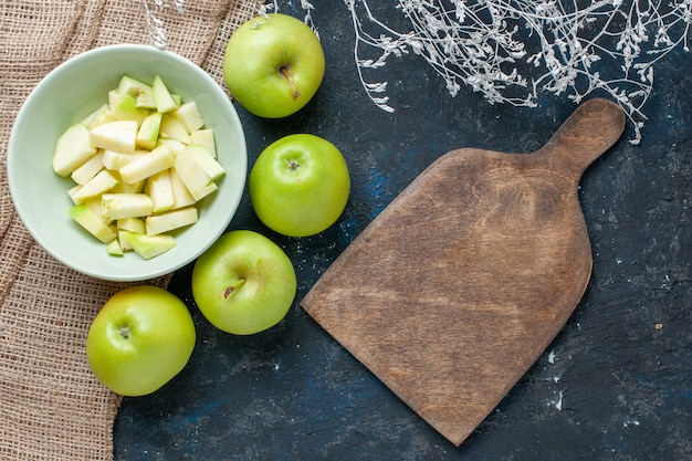 Top view of fresh green apples mellow and juicy with sliced apple inside plate on dark desk, fruit fresh health vitamine