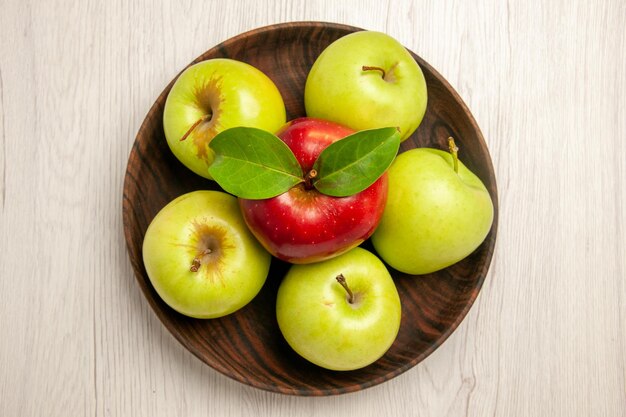 Вид сверху свежие зеленые яблоки, спелые и спелые фрукты на белом столе, цвет фруктов, свежее растение, красное дерево
