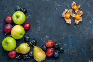 Foto gratuita vista dall'alto di mele verdi fresche con pere prugnoli e prugne sulla scrivania scura, frutta fresca di bacche dolci