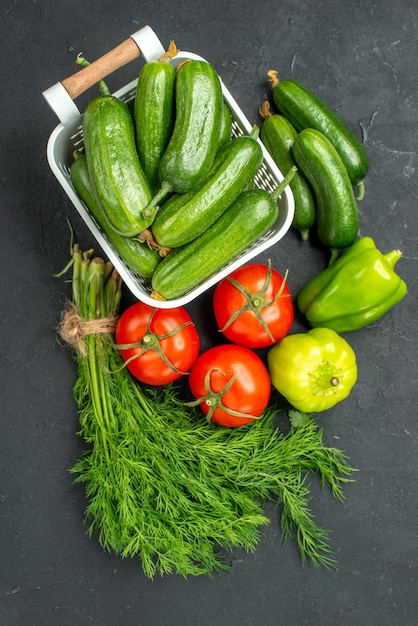 Top view fresh green cucumbers with greens and vegetables on a dark background