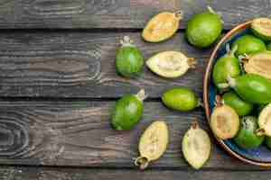 Free photo top view fresh green feijoas inside plate on wooden rustic desk fruit color photo juice ripe sour free space