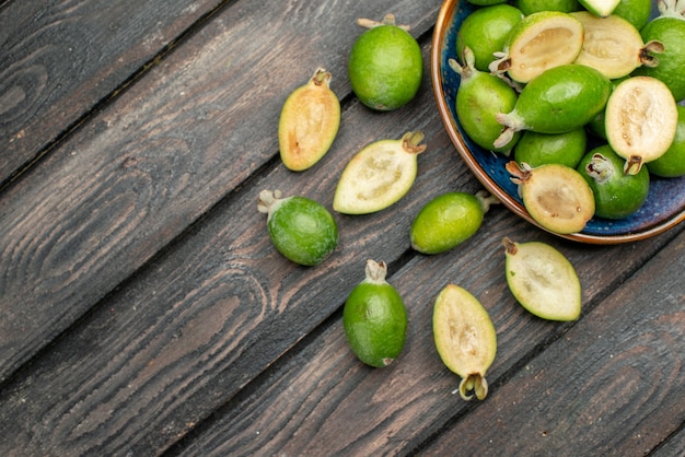 Top view fresh green feijoas inside plate on the wooden rustic desk fruit color photo juice ripe sour