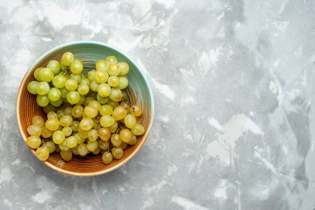 Top view of fresh green grapes inside brown plate on light, fresh fruit grape