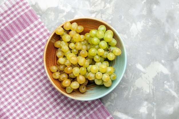 Top view of fresh green grapes inside plate on light, fruit fresh mellow juice