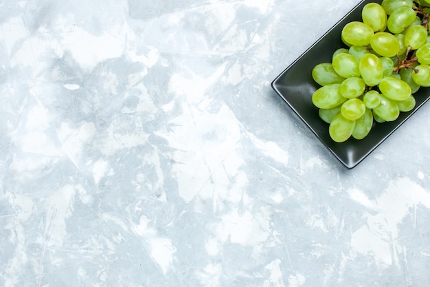 Free photo top view fresh green grapes mellow juicy fruits inside black form on light desk.