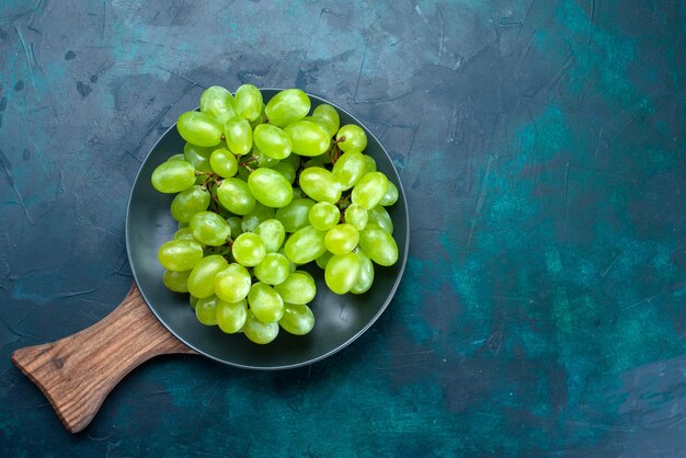 Free photo top view fresh green grapes mellow and juicy fruits inside plate on dark blue background.