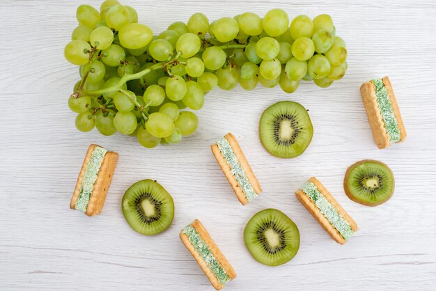 A top view fresh green grapes sour juicy and mellow with cookies and kiwis on the white background fruit ripe plant