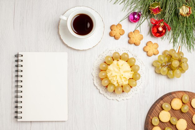 上面図新鮮な緑のブドウとお茶と白い机の上のケーキフルーツまろやかなジュース色レーズン