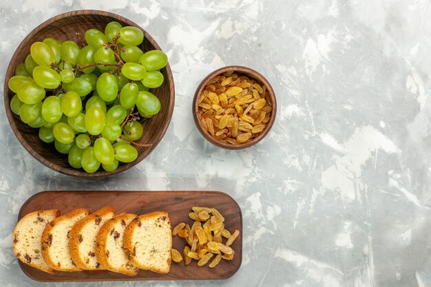 Top view fresh green grapes with raisins and cake slices on light-white desk