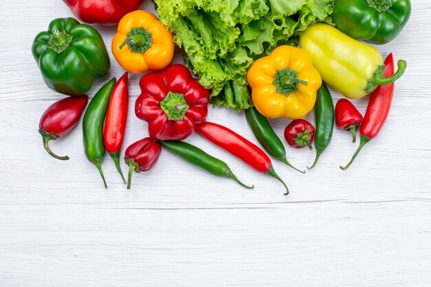 top view of fresh green salad along withed bell peppers and spicy peppers on light desk,  vegetable food meal ingredient